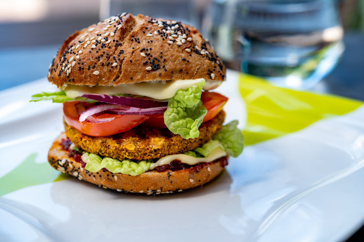 Veganer Burger mit knusprigen veganen Patty, frischem Salat, Tomaten, roten Zwiebeln und veganer Sauce im Mehrkornbrötchen – gesunde Fleischalternative, ideal für bewusste Ernährung und nachhaltigen Genuss.