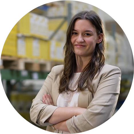 Junge Wela Mitarbeiterin mit verschrenkten Armen von einem Regal mit Produkten